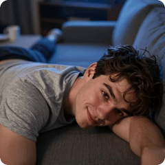A man in a grey sweater resting on a couch